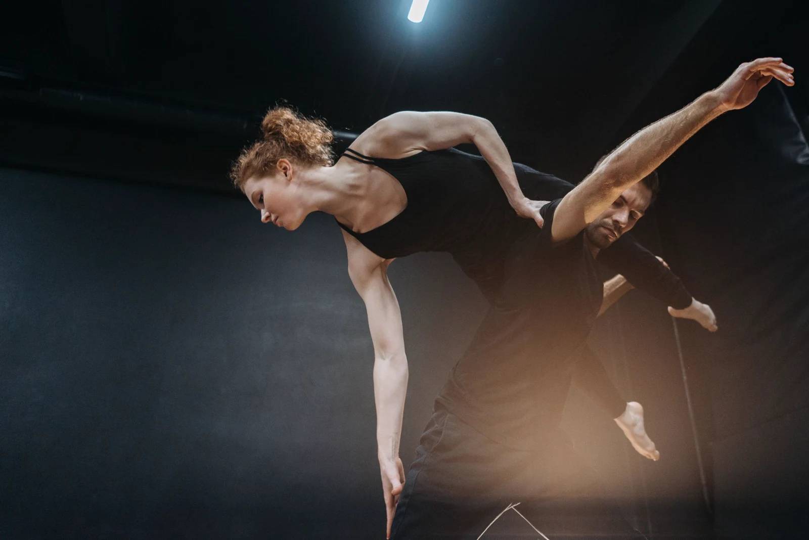 Coppia di danza sportiva che esegue una presa aerea su un palco scuro