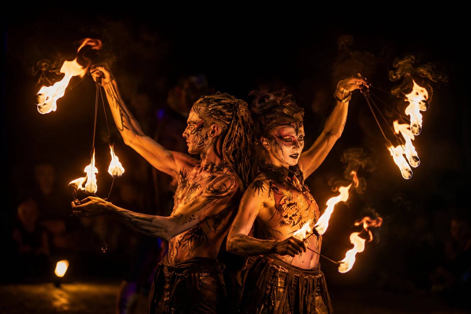 Fire show duo performing back to back with flaming props at night