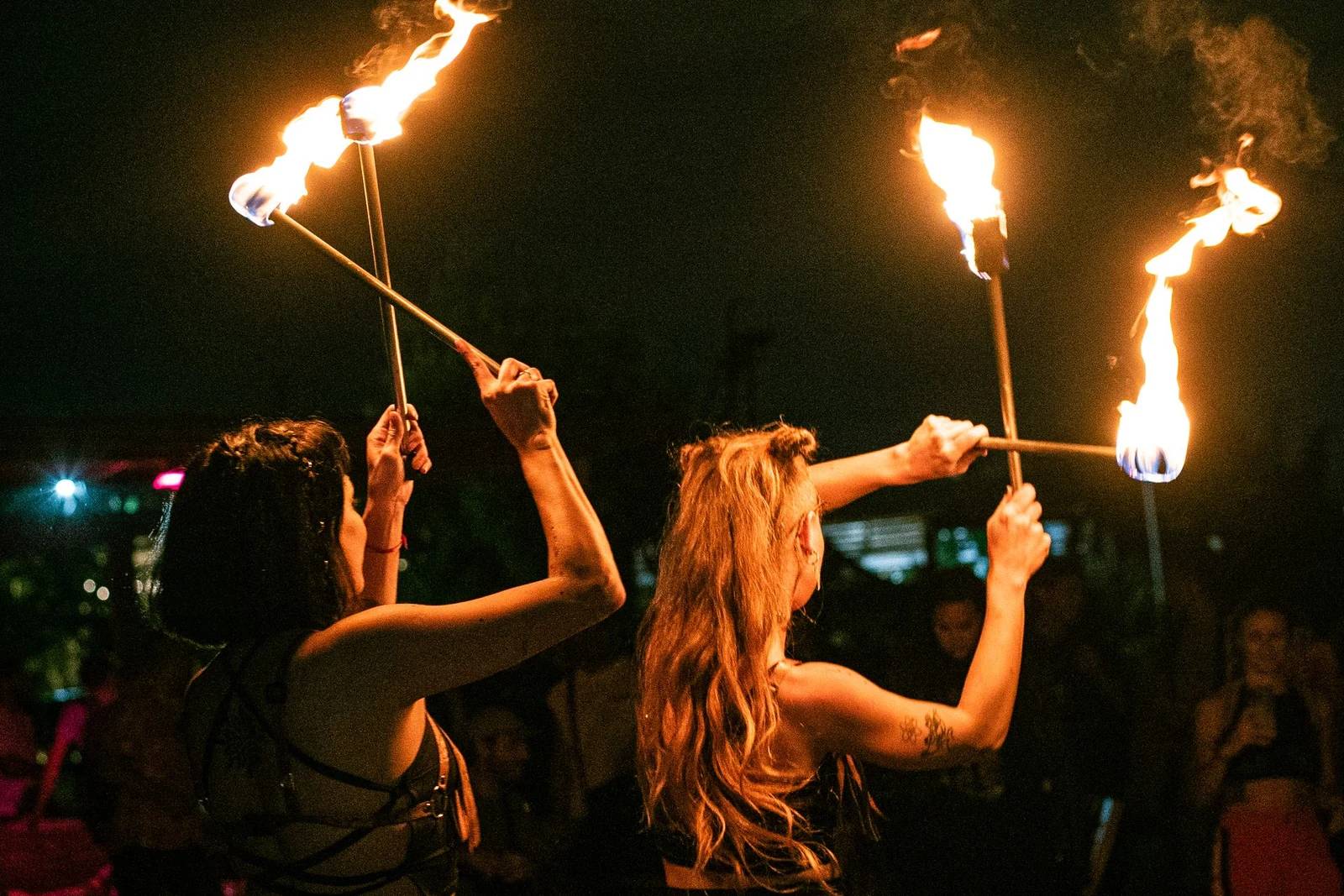 Fire show duo holding flaming torches during a night outdoor performance