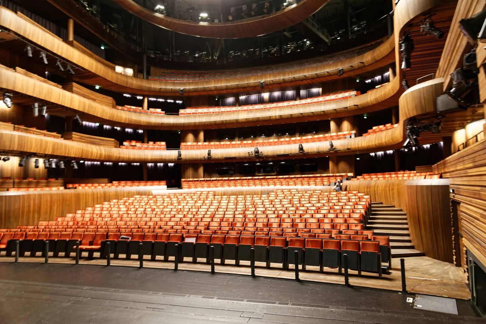 Empty cruise-style theater seen from the stage, orange seats and balconies under warm lights
